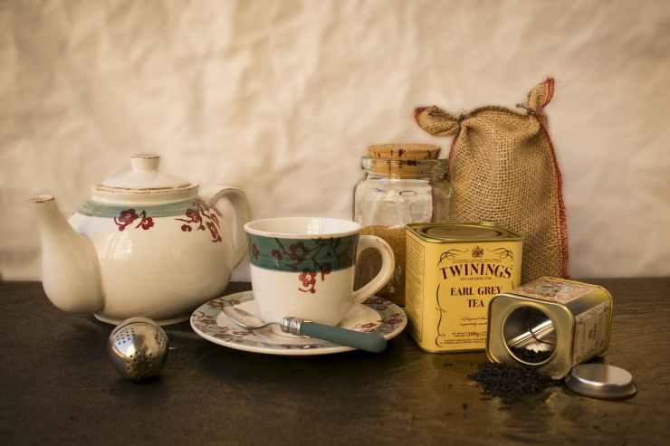 white and green ceramic mug beside ceramic teapot on table
